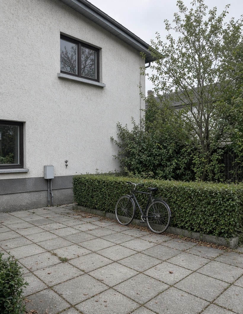 Vorgarten mit Betonplatten, Fahrrad an niedriger Hecke, Putzfassade ohne Hausnummer